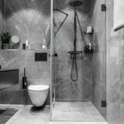 DMP - Nowoczesna łazienka w szarościach z kabiną typu walk-in, deszczownicą i marmurowymi płytkami. Minimalistyczny design z akcentami czerni i subtelnym oświetleniem.