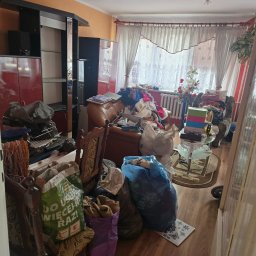 Gasiorex - Zabrudzone mieszkanie z meblami i workami pełnymi śmieci. Widok na pokój z bałaganem, ukazujący potrzebę profesjonalnego opróżniania i sprzątania.