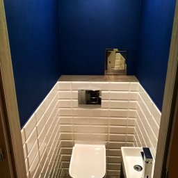 USŁUGI REMONTOWO-BUDOWLANE ROBERT JAMROZ - Kompaktowa toaleta w odcieniach bieli i granatu. Uwagę przykuwają białe, wypukłe płytki ułożone w oryginalny sposób oraz minimalistyczna umywalka.