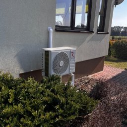 BestKlima Paulina Szczęsna - Biały klimatyzator Rotenso zamontowany na elewacji domu, z widoczną instalacją i otoczeniem zieleni. Ujęcie z poziomu gruntu.