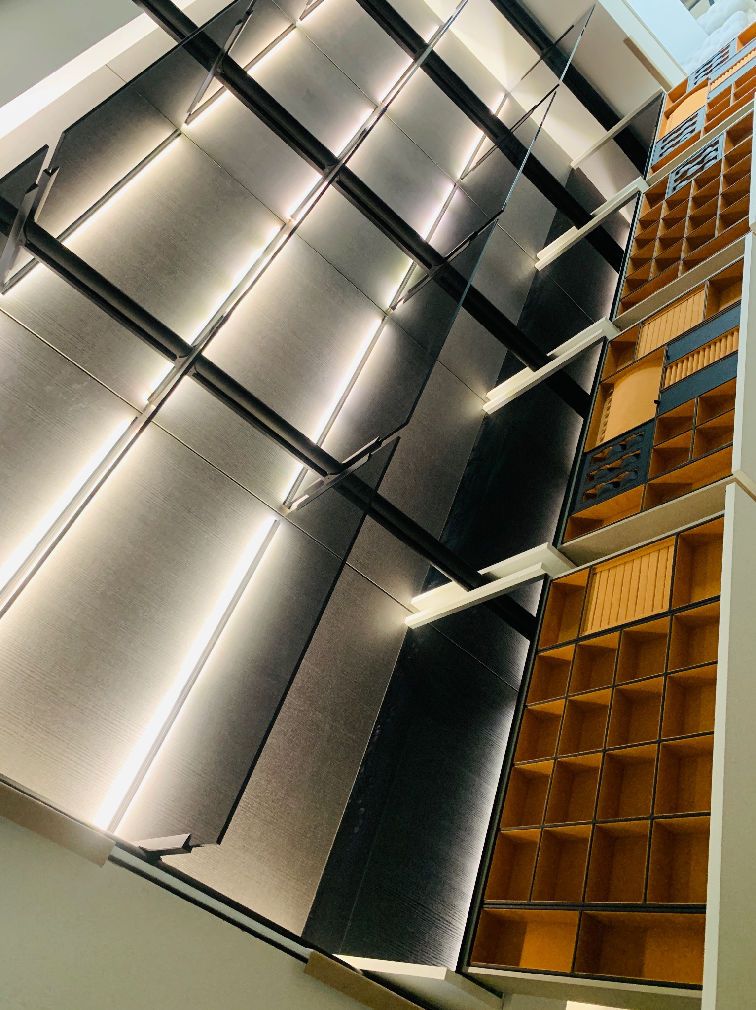 Nowoczesna kuchnia na wymiar: szare, podświetlane szafki z drewnianymi przegródkami, ujęcie pod kątem, prezentujące detale wykończenia i oświetlenia.