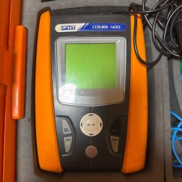 Install-Tech - Miernik wielofunkcyjny HT Combi 420 w pomarańczowej obudowie, z przewodami i akcesoriami, umieszczony w szarej, wyściełanej skrzynce transportowej.