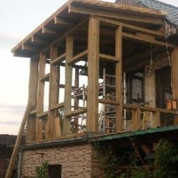 SolidHouse - Drewniana konstrukcja rozbudowy domu z widoczną drabiną opartą o ścianę. Surowy stan, przygotowanie do dalszych prac wykończeniowych.