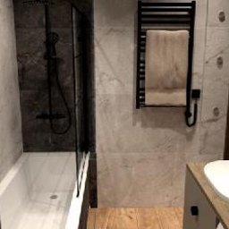 SolidHouse - Nowoczesna łazienka z wanną, kabiną prysznicową typu walk-in, umywalką nablatową i grzejnikiem drabinkowym. Wykończenie w odcieniach szarości i drewna.