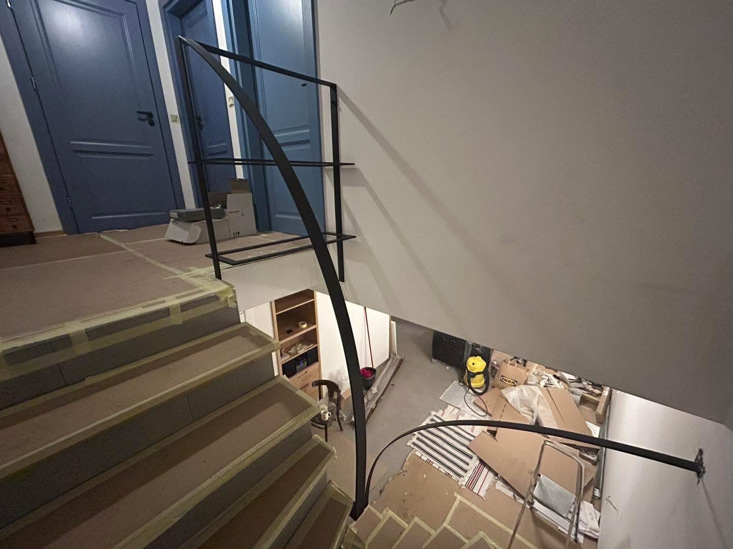 Czarna, metalowa poręcz schodowa w trakcie montażu, widok z góry. Schody zabezpieczone taśmą malarską. Usługa wykonana w Zawierciu.