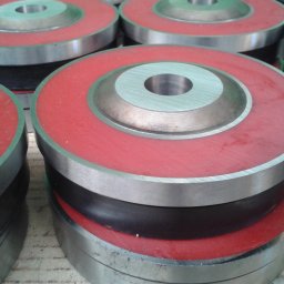 PPUH ZMETIS-BIS MAREK SOSNOWSKI - Metalowe elementy z czerwonymi i czarnymi wstawkami, ułożone jeden na drugim, tworzące okrągłe konstrukcje. Widoczne ślady obróbki.