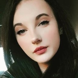 Tetiana-Dehod-Zajats - Portret młodej kobiety z ciemnymi włosami i delikatnym makijażem, skierowanej w stronę obiektywu, z subtelnym uśmiechem i naturalnym oświetleniem.