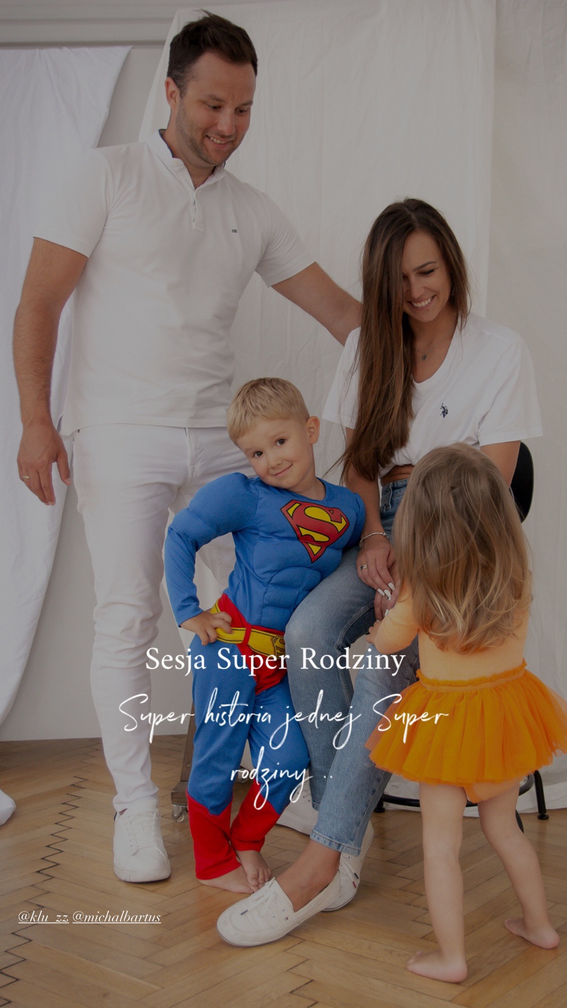 Uśmiechnięta rodzina w studio: tata, mama, syn w stroju Supermana i córka w tutu. Jasne tło, naturalne światło, radosna atmosfera sesji rodzinnej.