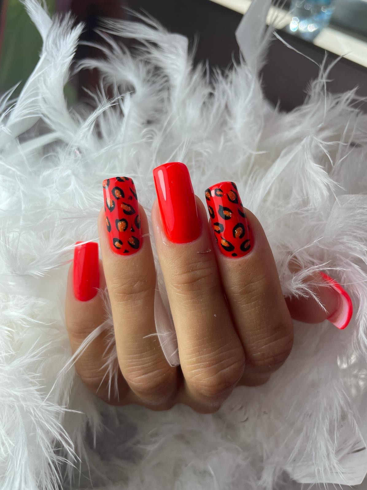 Czerwone, kwadratowe paznokcie z wzorem panterki na tle białych piór. Efektowny, modny design paznokci.