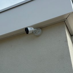 Patryk Security Systems - Kamera BCS zamontowana na elewacji budynku w Żarnowie. Widok z dołu, lekki kąt. Zabezpieczenia wizyjne dla domu i firmy.