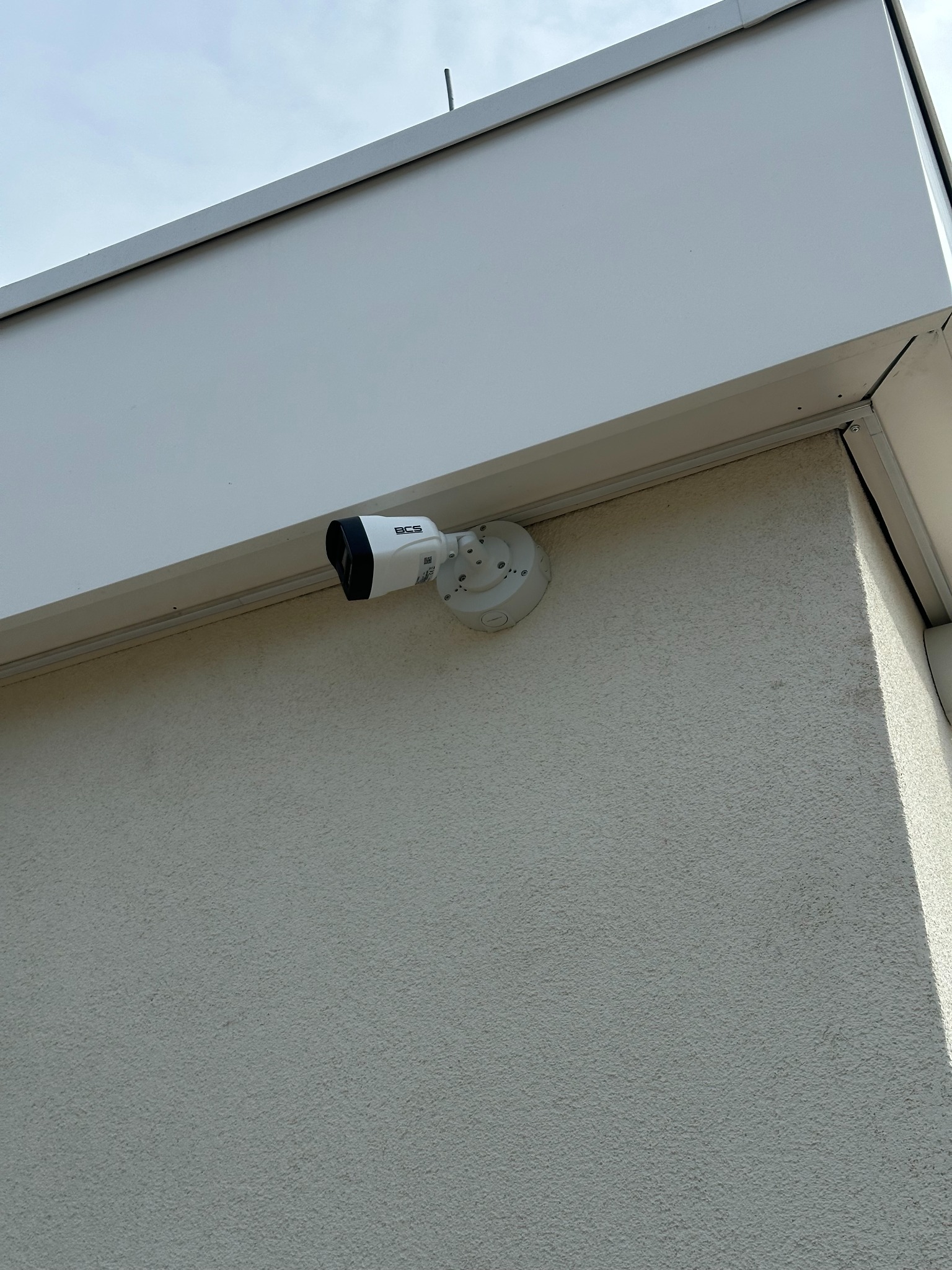 Kamera BCS zamontowana na elewacji budynku w Żarnowie. Widok z dołu, lekki kąt. Zabezpieczenia wizyjne dla domu i firmy.