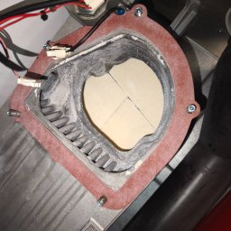 Kamil Góralski - Wnętrze pieca gazowego z widocznym palnikiem i elementami instalacji. Widoczne ślady użytkowania i osad. Detaliczny widok na komponenty pieca.