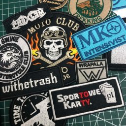 Waszehafty.pl Anna Stasiw - Kolekcja różnorodnych naszywek z haftowanymi wzorami i napisami, w tym motywy motocyklowe, sportowe i turystyczne, ułożonych na macie do cięcia.