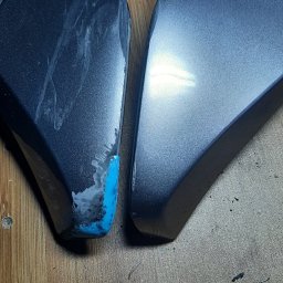 Lamintech - Uszkodzony element maszyny przed naprawą, z widocznymi śladami uszkodzeń i niebieskim podkładem, zestawiony z elementem w lepszym stanie.