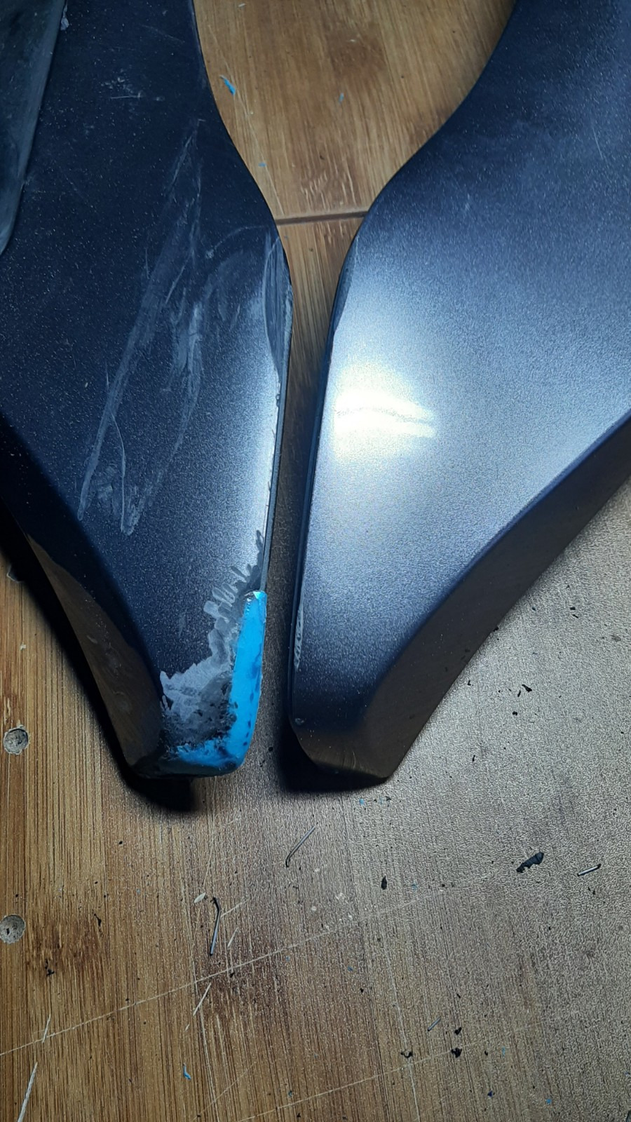 Uszkodzony element maszyny przed naprawą, z widocznymi śladami uszkodzeń i niebieskim podkładem, zestawiony z elementem w lepszym stanie.