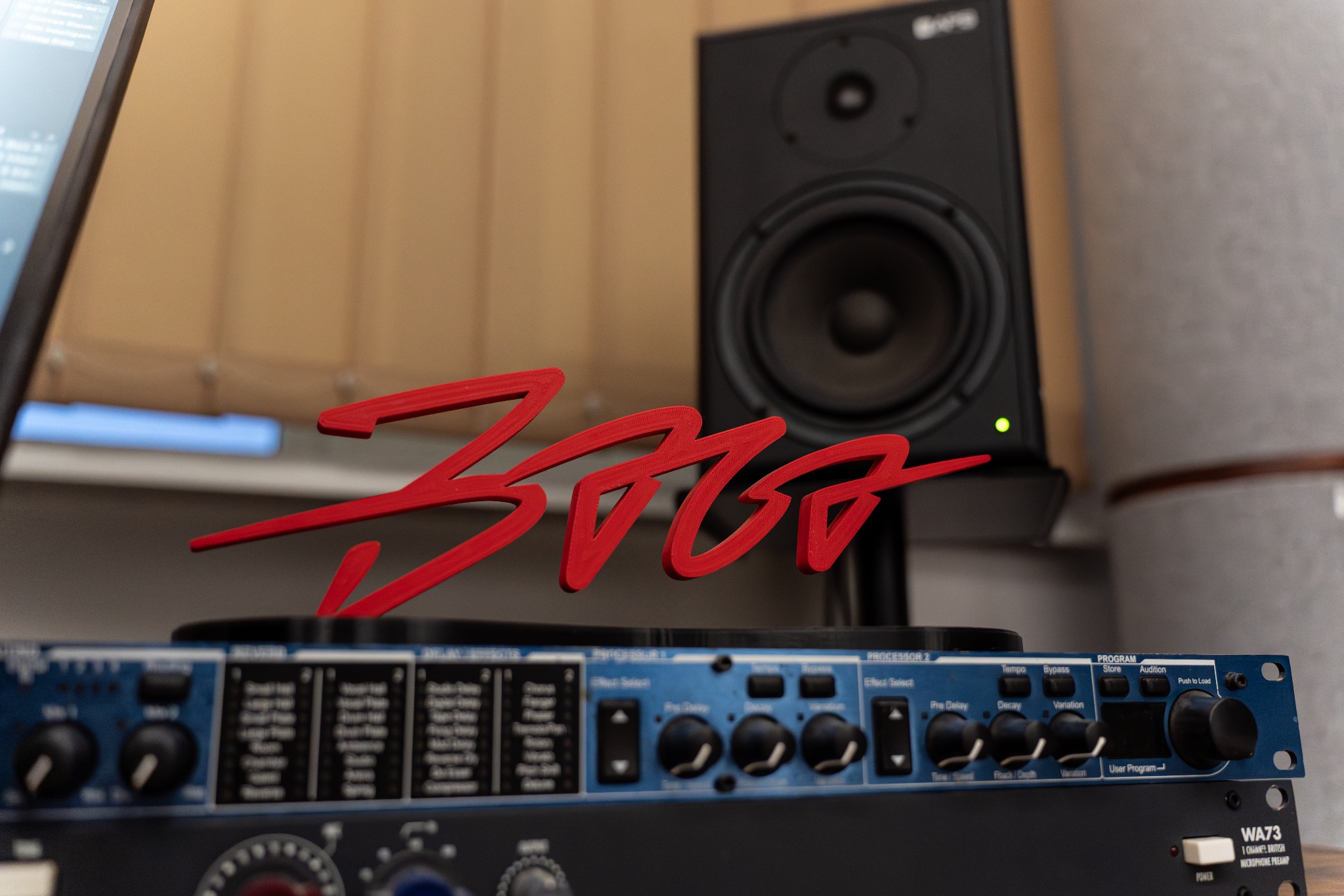 Sprzęt studyjny: monitor odsłuchowy, procesor efektów i czerwone logo. Elementy wyposażenia studia nagrań w zbliżeniu, z widocznymi detalami.