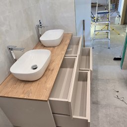 Design flow - Nowoczesna szafka łazienkowa z drewnianym blatem i dwiema umywalkami. Otwarta szuflada ukazuje wnętrze. W tle drabina i elementy wykończenia wnętrza.