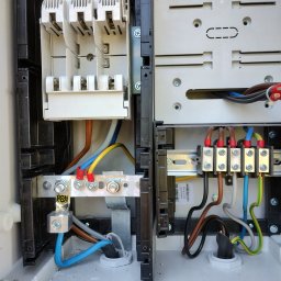 MAR VOLT - Otwarta skrzynka elektryczna z widocznymi bezpiecznikami, przewodami o różnych kolorach i metalowymi szynami. Detal przyłącza z oznaczeniem PEN.