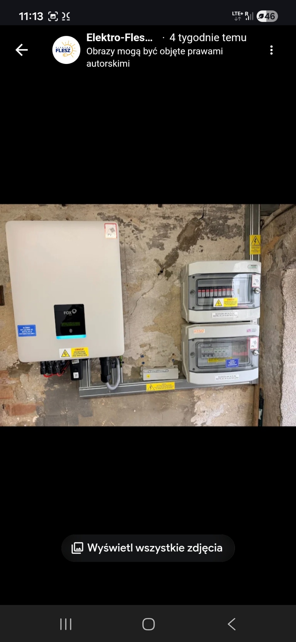 Biały inwerter FOX podłączony do instalacji elektrycznej na ścianie o surowym wykończeniu. Widoczne zabezpieczenia i okablowanie. Instalacja wewnątrz budynku.