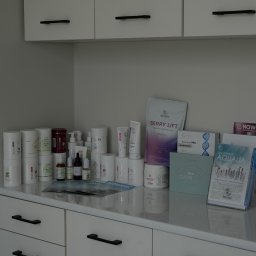 Bloom Skin Sp Z O.O. - Różnorodne produkty marki Renew na białej szafce z czarnymi uchwytami, w tle białe szafki wiszące. Kosmetyki do pielęgnacji twarzy i ciała w gabinecie.