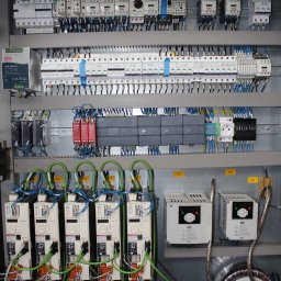 J&M Professional Małgorzata Antyga - Rozbudowana szafa sterownicza z licznymi elementami elektrycznymi, przewodami i modułami, ukazująca zaawansowany system kontroli i dystrybucji energii w przemysłowym otoczeniu.