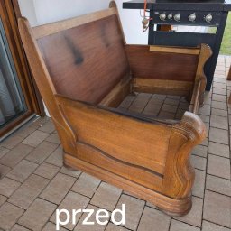 Karol Anczarski - Drewniany, rozłożony stelaż łóżka z widocznymi śladami użytkowania, ustawiony na zewnątrz obok grilla. Zdjęcie 'przed' renowacją lub naprawą.