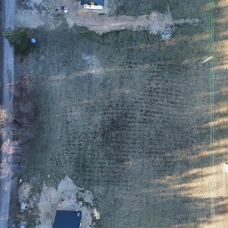 Taxi Wojciech Żuk - Zdjęcie z drona przedstawia rozległą działkę z widocznymi śladami po pracach ziemnych, graniczącą z lasem i drogą. W tle widoczny dom z ciemnym dachem.