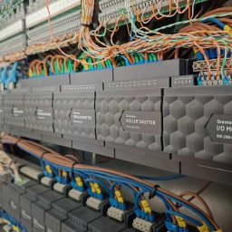 ELEKTRO-SMART Szymon Mazurek - Szare moduły sterujące roletami Grenton Roller Shutter RSH-203-D-01 i moduł I/O Module INO-288-D-01, z podłączonymi przewodami w różnych kolorach, w szafie sterowniczej.
