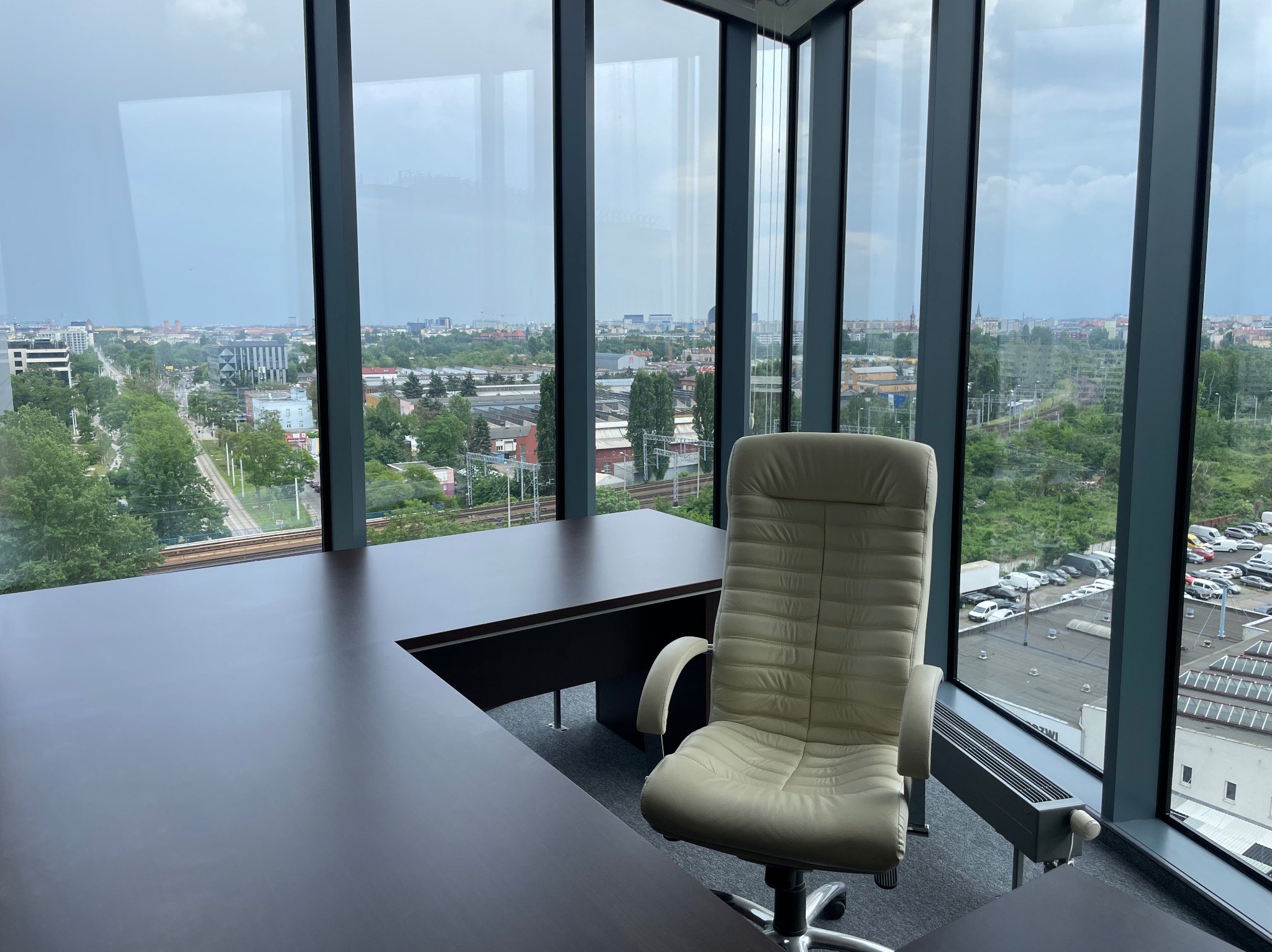 Nowoczesne biuro z widokiem na miasto przez panoramiczne okna. Biurko z krzesłem biurowym. Minimalistyczny design, jasne wnętrze, przestrzeń do pracy.