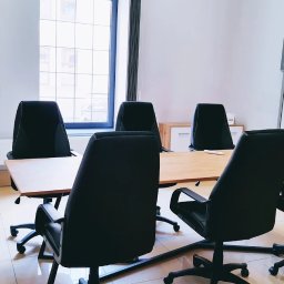 ENGLISH NAVIGATOR SPÓŁKA Z OGRANICZONĄ ODPOWIEDZIALNOŚCIĄ - Sala lekcyjna z dużym oknem, stołem konferencyjnym i krzesłami obrotowymi. Na ścianie biała tablica suchościeralna. W rogu szafka z kwiatami.