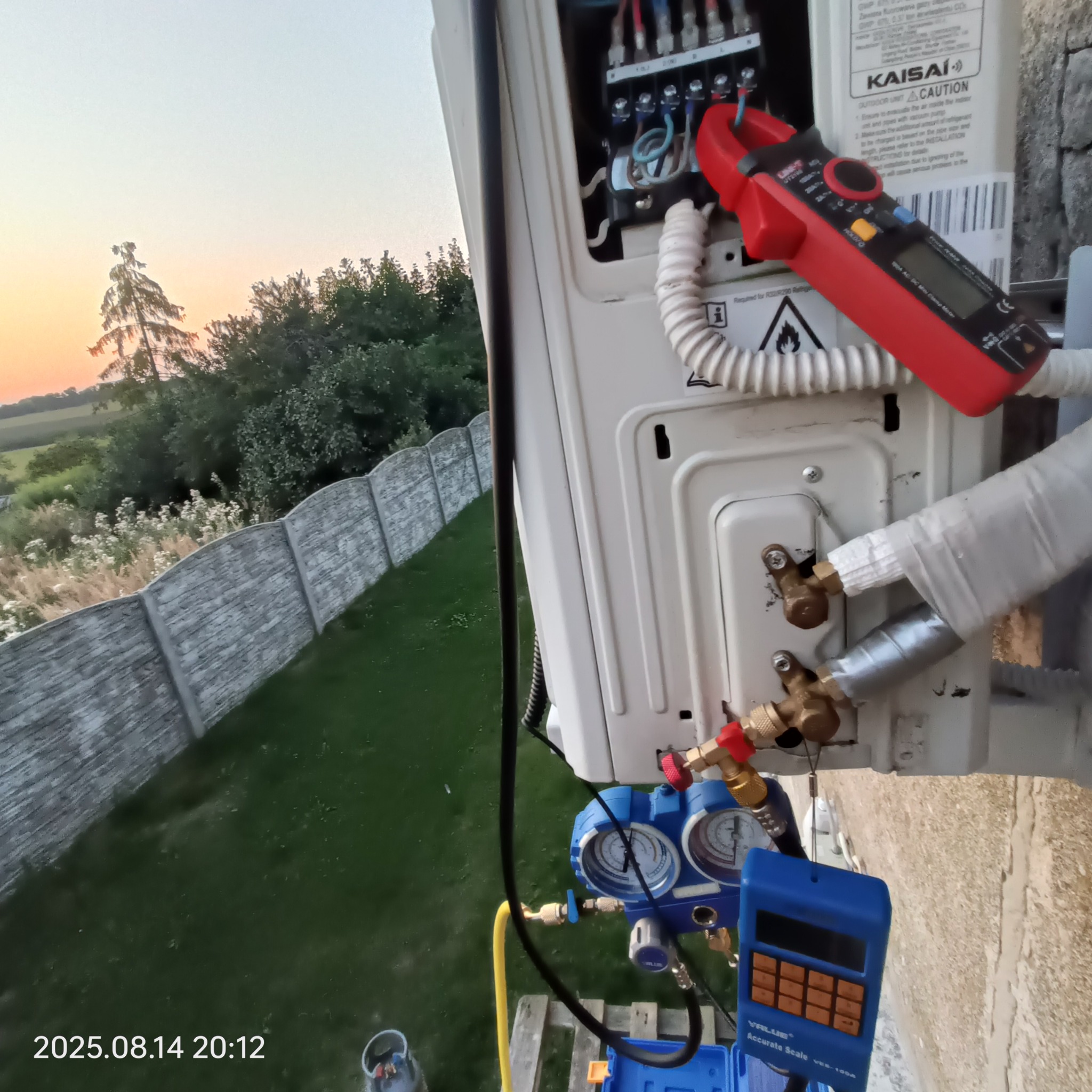 Serwis klimatyzacji Kaisai w Miliczu: jednostka zewnętrzna z podłączonymi narzędziami diagnostycznymi, widoczne przewody i miernik cęgowy. Prace serwisowe w toku.