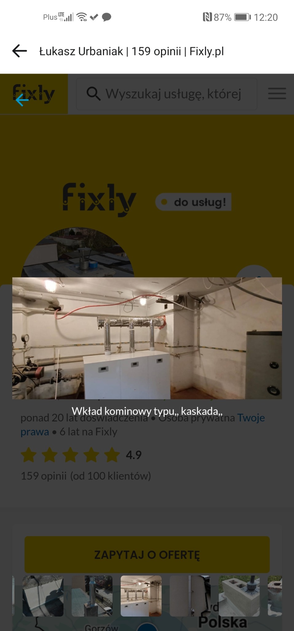 Kaskadowy wkład kominowy w piwnicy, widoczne rury i instalacje. Biała obudowa wkładu, surowe ściany. Ujęcie z bliska, oświetlenie jarzeniowe.