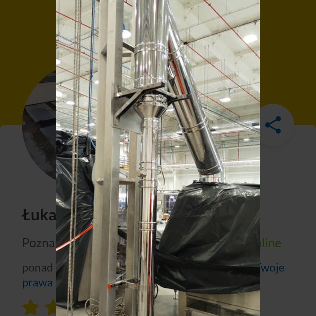 Błyszcząca, metalowa instalacja przemysłowa z rur, prawdopodobnie wentylacyjna, zamontowana w hali produkcyjnej z widocznymi elementami konstrukcyjnymi.