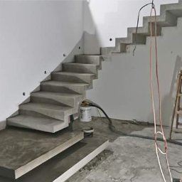 Schody betonowe Fran-Bud - Surowe, betonowe schody w jasnym wnętrzu, z widocznymi śladami prac budowlanych i narzędziami. Minimalistyczny design, schody wspornikowe z oświetleniem punktowym.