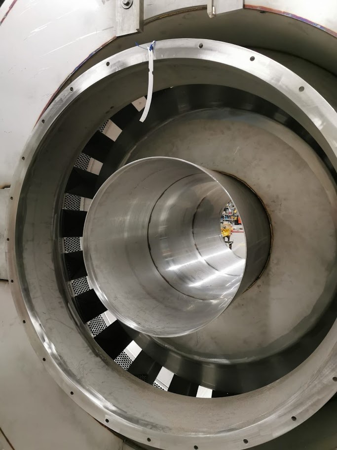Wnętrze konstrukcji ze stali nierdzewnej z perforowanymi elementami, widoczne spawane łączenia. Elementy cylindryczne wewnątrz większej obudowy.