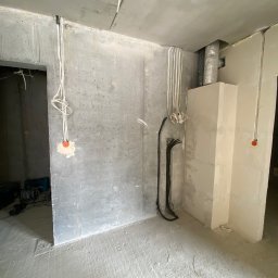 FixHouse Grzegorz Rzepa - Surowy stan wnętrza w trakcie prac wykończeniowych: widoczne przewody elektryczne, ściany z betonu komórkowego i wylewka podłogowa. Etap instalacji przed dalszymi pracami.