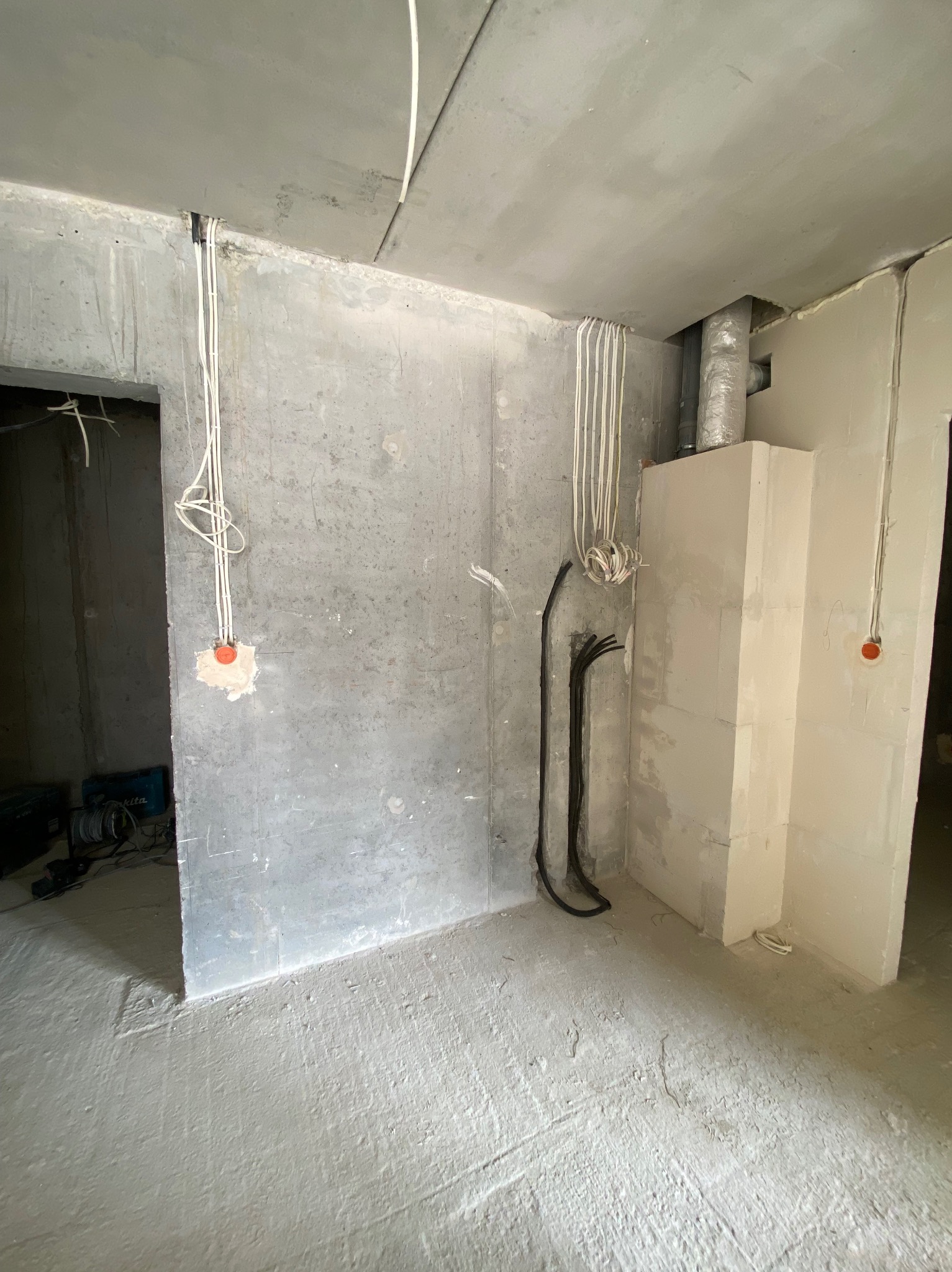 Surowy stan wnętrza w trakcie prac wykończeniowych: widoczne przewody elektryczne, ściany z betonu komórkowego i wylewka podłogowa. Etap instalacji przed dalszymi pracami.