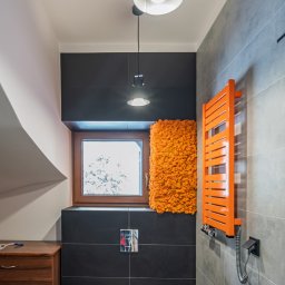 SENDO - Nowoczesna łazienka na poddaszu z czarnymi i szarymi płytkami, pomarańczowym grzejnikiem i mchem dekoracyjnym przy oknie. Minimalistyczne oświetlenie.