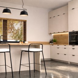 DRZEWIECKA DESIGN - Jasna kuchnia z drewnianym blatem, czarnymi lampami i lodówką. Dwa czarne hokery z białymi siedziskami przy blacie. Żaluzje drewniane w oknie.