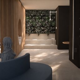 DRZEWIECKA DESIGN - Nowoczesne biuro z drewnianymi elementami, zieloną ścianą i nietypową strefą relaksu z podestami i okrągłą sofą. Osoba w szarym stroju w tle dodaje skali.