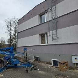 Somar - Montaż klimatyzacji zewnętrznej na elewacji budynku z użyciem podnośnika. Widoczna drabina na ścianie i karton po urządzeniu.