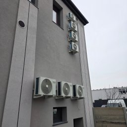 Somar - Szereg klimatyzatorów ANDE zamontowanych na szarej elewacji budynku, widoczne jednostki zewnętrzne, rury instalacyjne i fragment otoczenia.