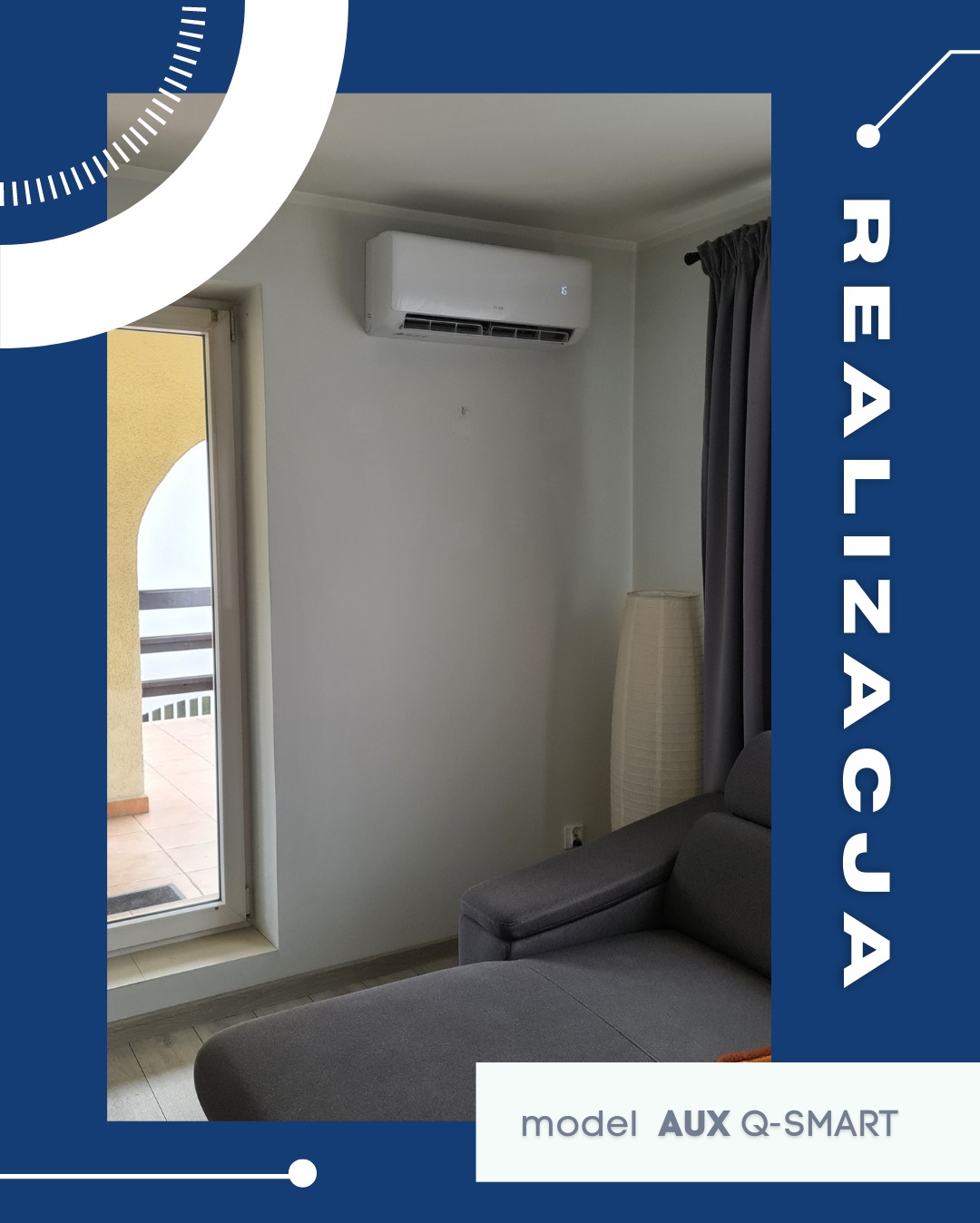 Biały klimatyzator AUX Q-SMART zamontowany na ścianie w jasnym pokoju z szarą sofą i oknem balkonowym. Widoczna zasłona i lampa podłogowa. Realizacja.