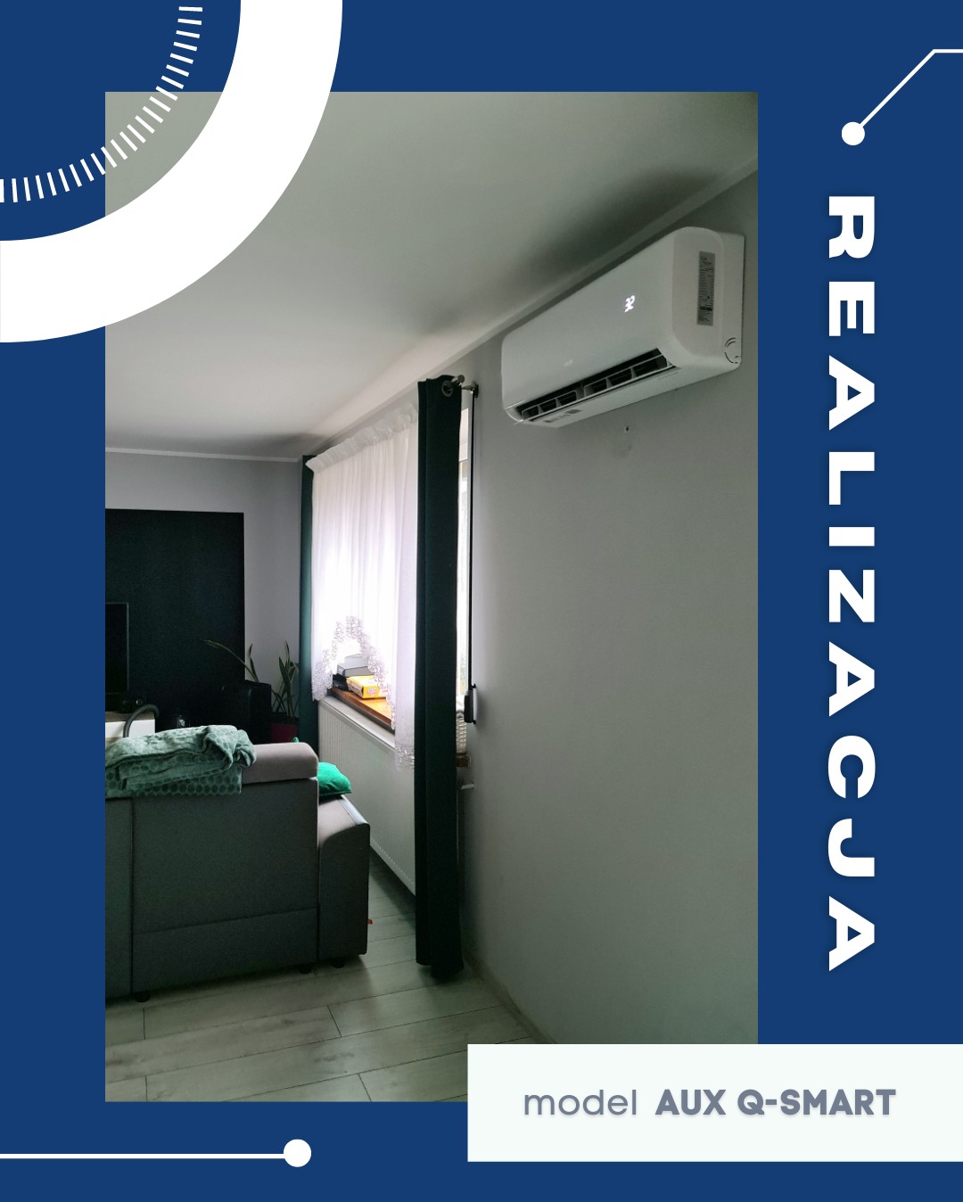 Biały klimatyzator AUX Q-SMART zamontowany na szarej ścianie w salonie. Widok z boku, okno z firanką w tle. Częściowo widoczna sofa i podłoga.