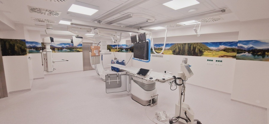 Nowoczesne wnętrze gabinetu medycznego z zaawansowaną aparaturą diagnostyczną. Na ścianach dekoracyjne panele z motywem górskiego krajobrazu. Jasne, przestronne pomieszczenie.