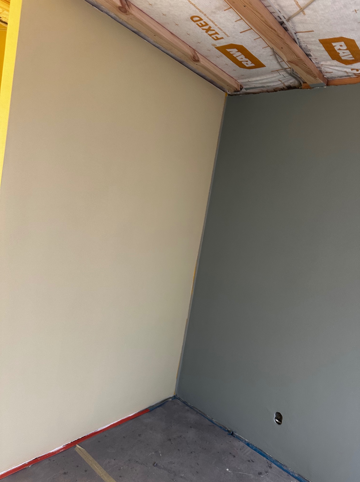 Pomieszczenie po malowaniu ścian na dwa kolory: beżowy i szary. Widoczne zabezpieczenia podłogi i sufitu. Świeżo pomalowane ściany w nowym budynku.