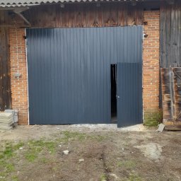 Sławomir - Szara brama garażowa z drzwiczkami, zamontowana w budynku z cegły i drewna. Widoczne uszczelnienie. Realizacja w Iłży.