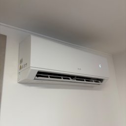 DKV INSTAL - Biały klimatyzator AUX zamontowany na ścianie, widoczny wyświetlacz z temperaturą 16 stopni Celsjusza. Minimalistyczny design, jasne wnętrze.