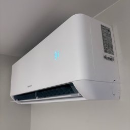 DKV INSTAL - Biały klimatyzator Nordis na ścianie, wyświetlający temperaturę 31 stopni. Widoczna tabliczka znamionowa i filtr powietrza. Minimalistyczny design w jasnym wnętrzu.