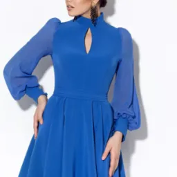 Modelka prezentuje kobiecą, kobaltową sukienkę z bufetowymi rękawami i stójką z wycięciem, uzupełnioną o duże, wiszące kolczyki na białym tle.